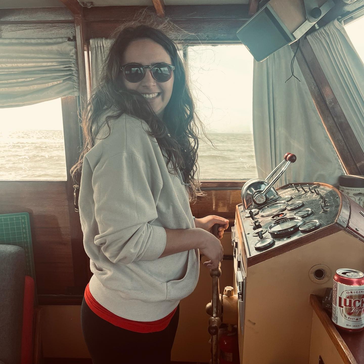 A girl with sunglasses and dark hair steering a boat